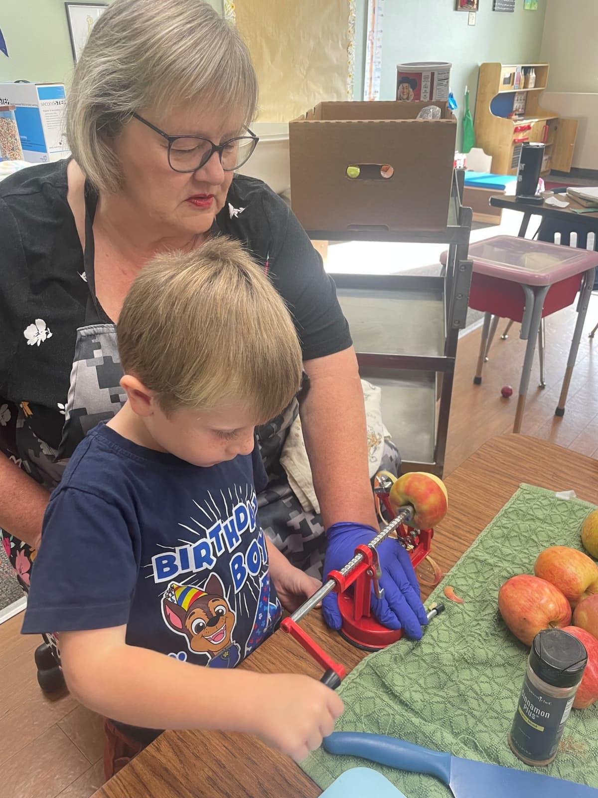 A teacher and a child preparing apple pie