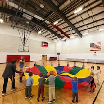Preschool students enjoying a parachute activity in the gym