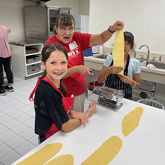 Students and adults making pasta in the school kitchen