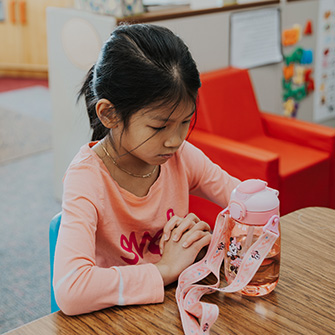 Student praying at her desk