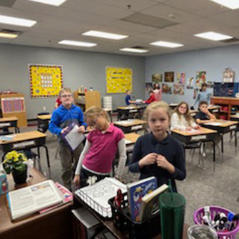 students standing at teachers desk